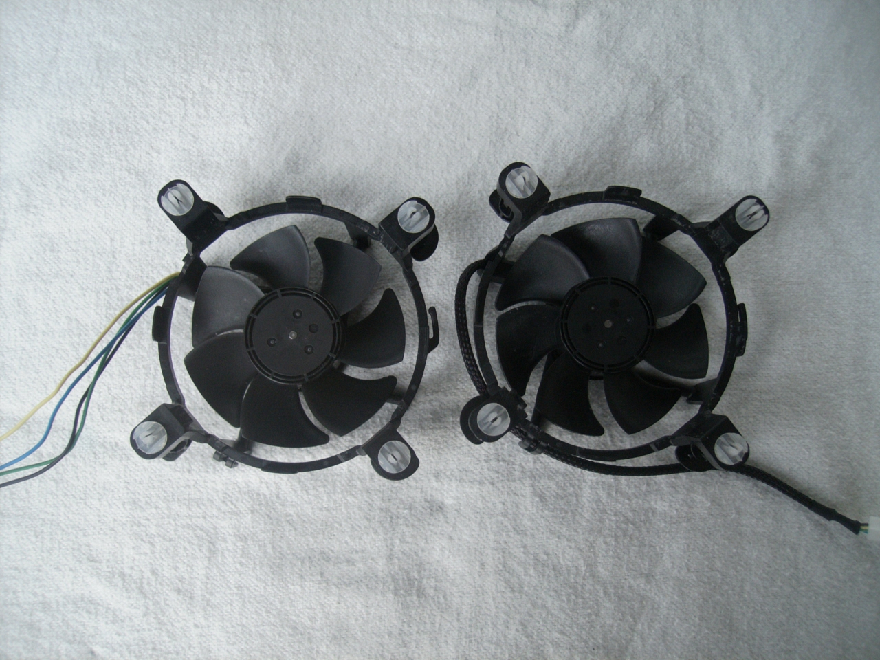The low end cooler 7-blade fan is rated for 0.2 amps at 12 volts. At full throttle, this fan spins at 3,000 RPM. At their thickest, the blades measure 3mm. The fan itself is 26 mm thick, excluding the cooler mounts. The higher end cooler fan has a rating of 0.28 amps at 12 volts, slightly higher than the all-aluminium cooler's fan. Oddly, it has the same maximum speed, 3,000 RPM. The overall dimensions are the same, except for the fin thickness and the core. The impeller blades are noticeable thicker than the other cooler, up to 3.5mm thick, and thicker for a larger section of each blade.